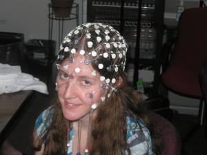 girl wearing an EEG cap, with white electrodes in a hair-net-like cap over her head